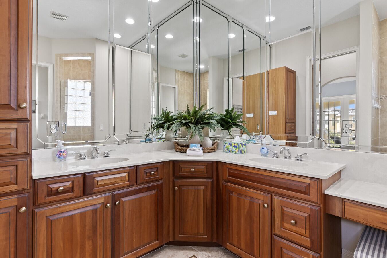 Une salle de bain moderne avec des meubles en bois, un grand miroir et un plan de toilette blanc.