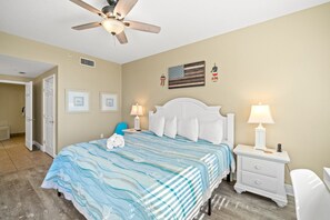 Una camera da letto con un letto, comodini bianchi, una ventola a soffitto e decorazioni a parete tra cui una bandiera e una lanterna.