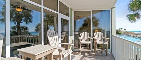 Un balcon avec une piscine, des chaises blanches et une table.