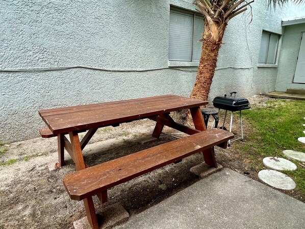 A wooden picnic table with benches, a grill, and a palm tree in a backyard. - Waymar Isle 6 - Beach Walk (Fort Walton Beach)