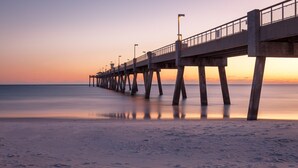 Un muelle que se adentra en aguas tranquilas al atardecer.