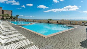 A pool area with lounge chairs and a view of the ocean. - Waters Edge 404 - Okaloosa Dreamin' (Fort Walton Beach)