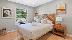 A bedroom with a bed, bedside table, and artwork on the walls. - Marbella Lane - Chic Abode w Mountain Skyline (Pacifica)