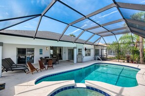 A swimming pool with a glass enclosure, lounge chairs, and a patio area. - Life's Porpoises - 29 Coconut Ct (Palm Coast)