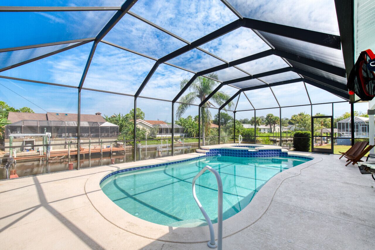 An indoor swimming pool with a clear view of the surrounding area, including houses and palm trees.