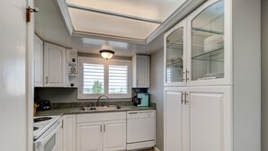 A modern kitchen with white cabinetry, a built-in oven, a sink, and a coffee maker. - Sunny Ormond Beach SOB Condo, Pool, No Drive Beach (Ormond Beach)