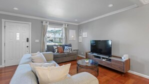 A living room with a sofa, a television, and a coffee table. - Marbella Lane - Buckingham Place Laundry P (Pacifica)