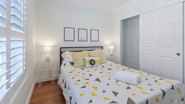 A neatly arranged bedroom with a bed, bedside lamps, and a small table. - Marbella Lane - Buckingham Place Laundry P (Pacifica)