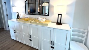 A white cabinet with multiple doors, a mirror above it, and two lamps on either side. - 2109 Landfall Way (Seabrook Island)