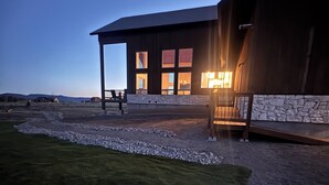 A modern building with a stone facade, large windows, and a covered outdoor area. - 6-bedroom cabin-lake access .5 mile-hot tub-sauna-6' spiral slide-Modern Comfort (Island Park)