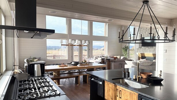 A modern kitchen with a gas stove, Bosch dishwasher, wooden cabinets, and large windows offering a view of the outdoors. - 6-bedroom cabin-lake access .5 mile-hot tub-sauna-6' spiral slide-Modern Comfort (Island Park)