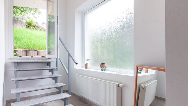 En trappa som leder upp till en liten plattform med utsikt över en trädgård.