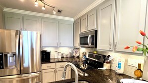 Una cocina moderna con electrodomésticos de acero inoxidable, encimera de granito y armarios de tonos claros.