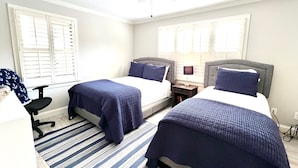 Un dormitorio con dos camas, un ventilador de techo y un tapete a rayas.