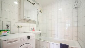 Ein Badezimmer mit Waschmaschine, Waschbecken und Badewanne.