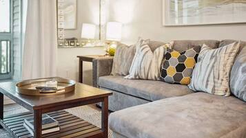 A living room with a grey sofa, a wooden coffee table, and a tray with books.