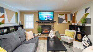 A living room with a fireplace, a flat-screen TV mounted above it, and a sofa set. - 306 Jason Court, Woodstock (Woodstock)