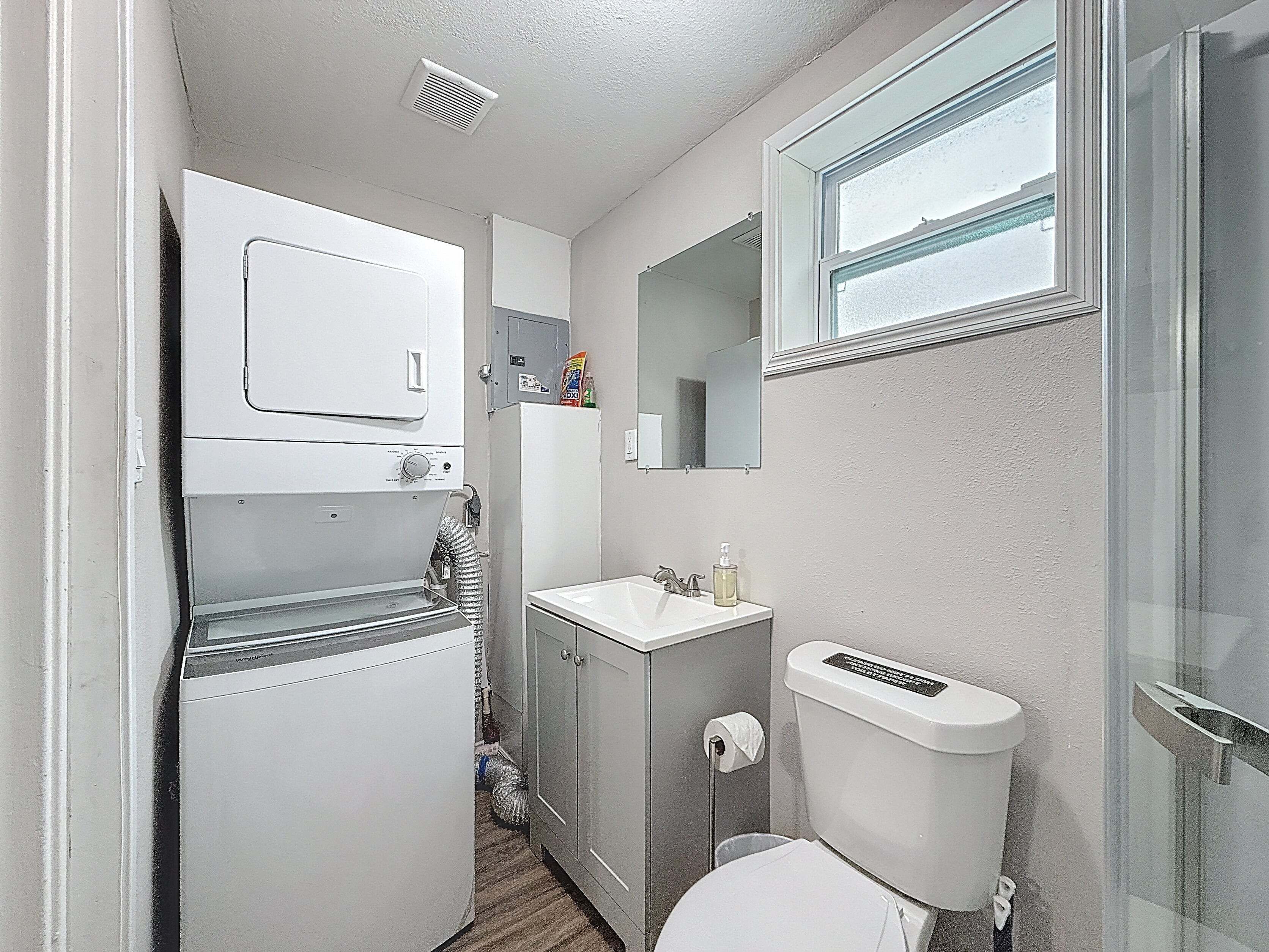A compact bathroom with a toilet, sink, mirror, and a small window.
