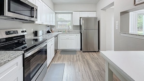 A modern kitchen with white cabinets, stainless steel appliances, and a granite countertop. - 3012 E Norfolk Street (Tampa)