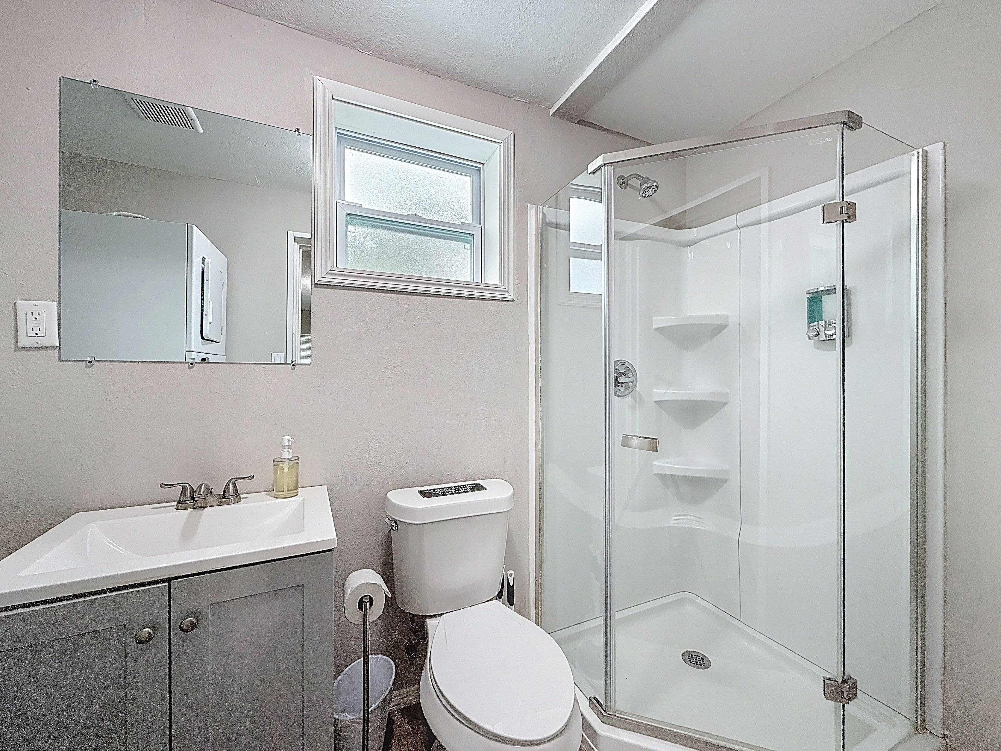A bathroom with a sink, toilet, and a glass-enclosed shower.