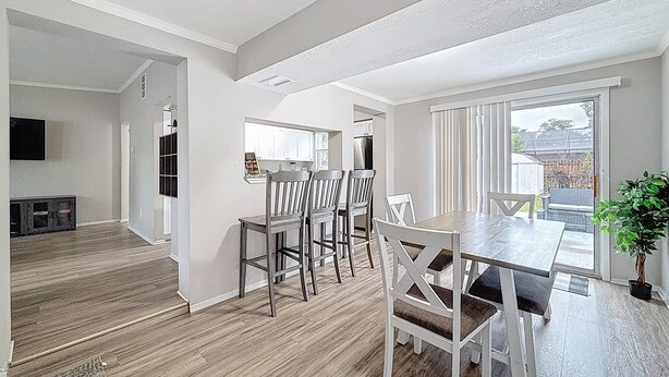 A spacious living area with a wooden floor, a dining table with chairs, and a kitchen in the background. - 3012 E Norfolk Street (Tampa)