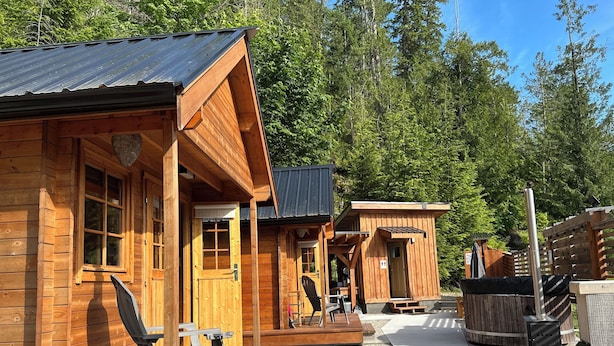 A wooden cabin with a porch, a dining area, and a sauna.