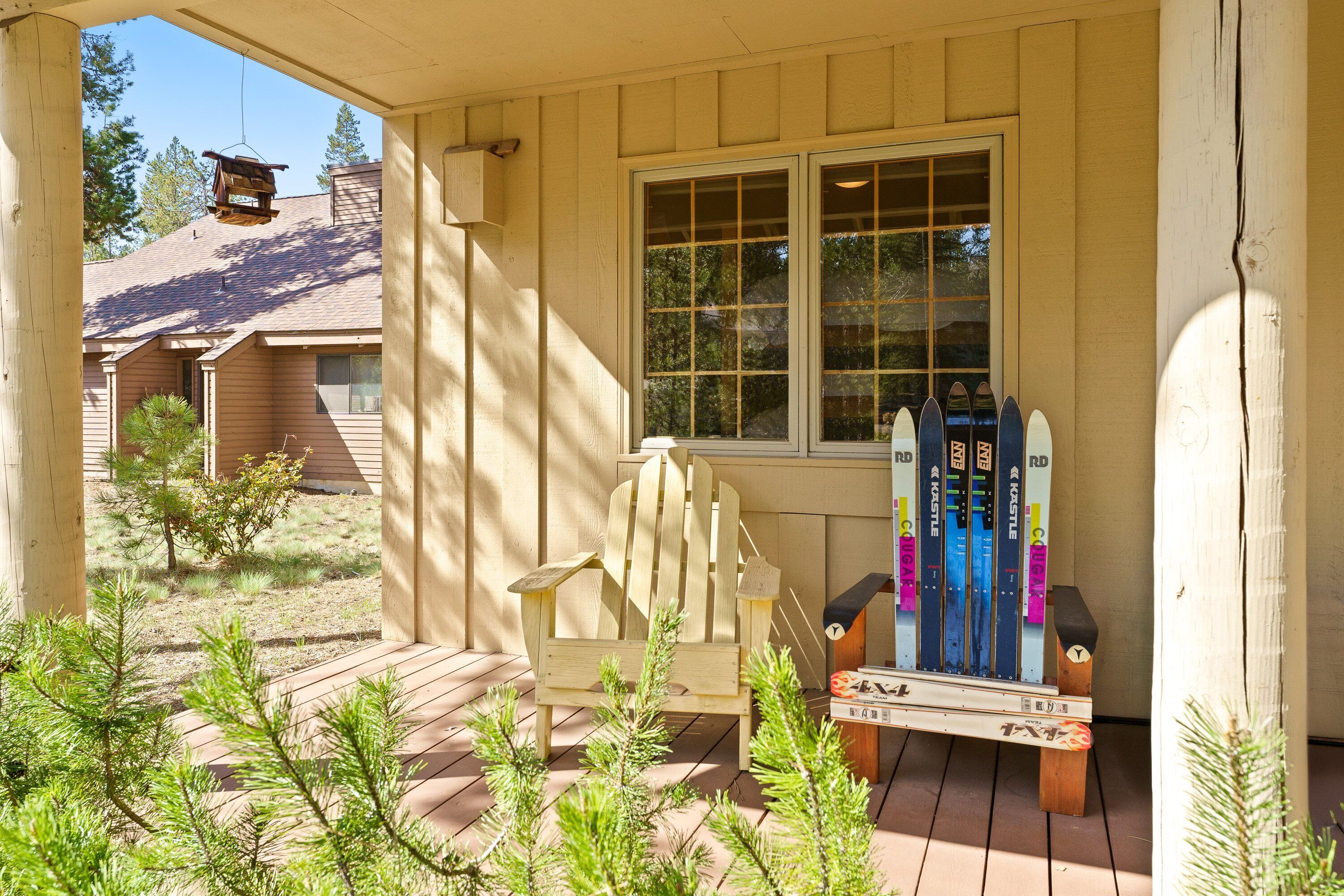 A wooden porch with a wooden chair, a window, and a row of skis leaning against the wall.