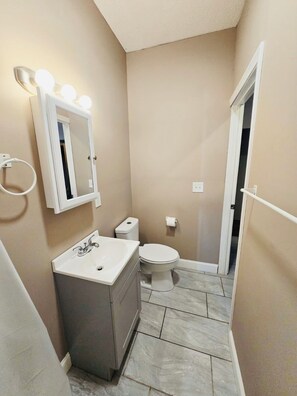 A compact bathroom with a vanity, a toilet, and a mirror with lights. - Nice apartment near Whole Foods, Brown University, Miriam, RI Hospital, Downtown (Providence)