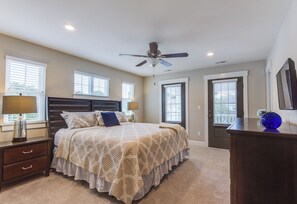 Une chambre à coucher avec un lit, des lampes de chevet, un ventilateur de plafond et une commode avec un miroir.