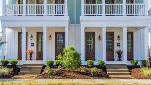 A symmetrical two-story house with a front porch, a central chimney, and a small garden area. - 408b The Lynnhaven House Spacious 4 BR Townhouse Walking Distance to the Beach and Boardwalk (Virginia Beach)