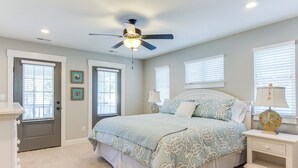 A bedroom with a bed, a ceiling fan, and two bedside tables with lamps. - 404a The Hilltop House (Virginia Beach)