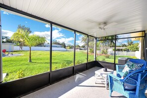 A covered patio with large windows, a ceiling fan, and outdoor furniture. - 4544 Auburn Ave (Fort Myers)