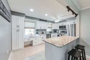 A modern kitchen with white cabinets, granite countertops, and stainless steel appliances. - 4544 Auburn Ave (Fort Myers)