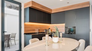 Une cuisine moderne avec une table de salle à manger ronde, des appareils électroménagers intégrés et une grande fenêtre.