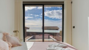 Une chambre avec une grande porte-fenêtre coulissante donnant sur un balcon, un lit agrémenté de coussins moelleux et une serviette soigneusement pliée posée sur le lit.