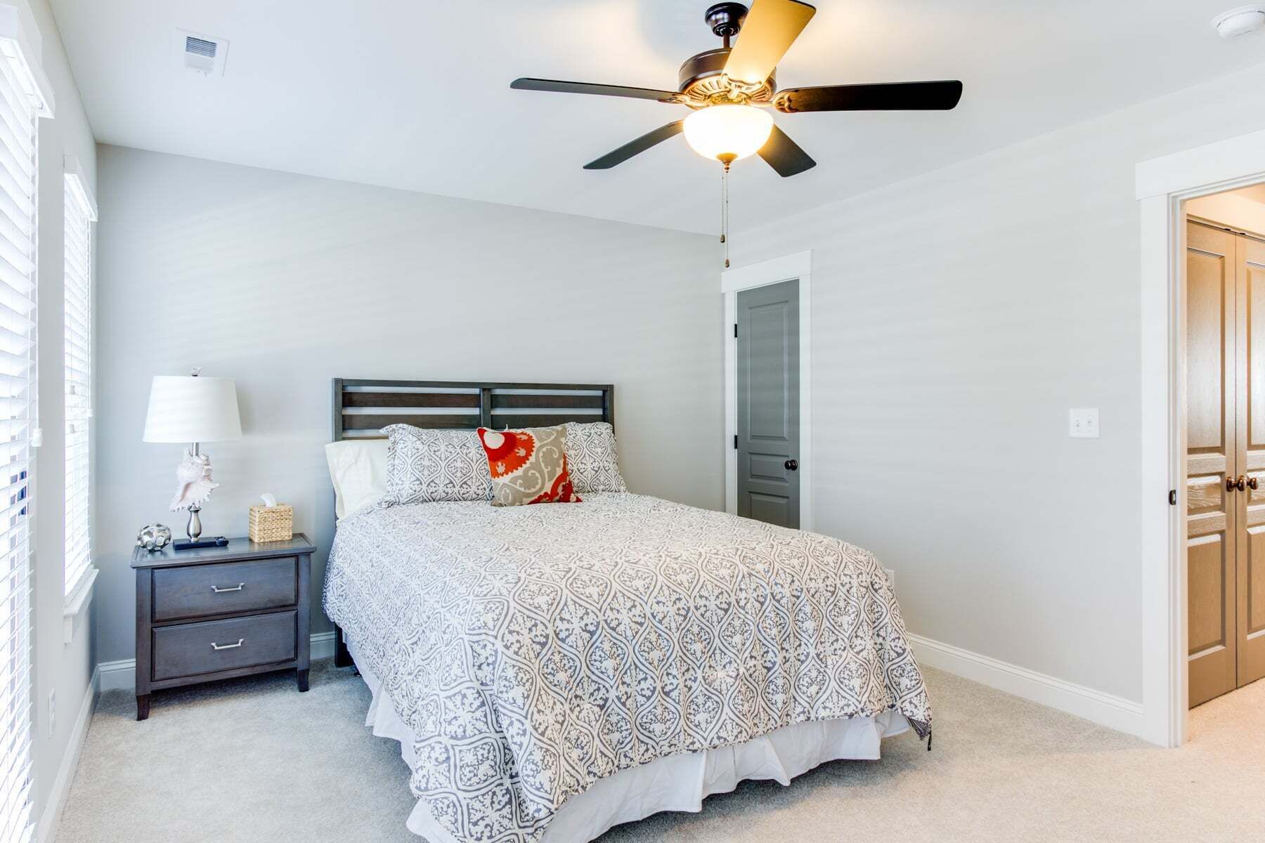 A bedroom with a bed, nightstand, lamp, and ceiling fan.