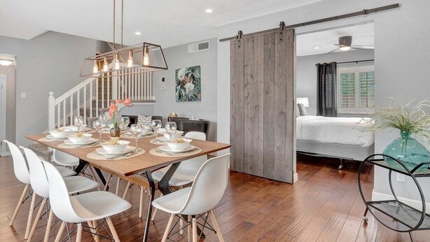 A modern dining area with a wooden table set for six, white chairs, and a pendant light. - 49th St (Scottsdale)
