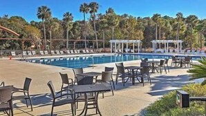A poolside area with lounge chairs and tables, a covered seating area, and a clear blue sky. - 601 Double Eagle Trace (Seabrook Island)