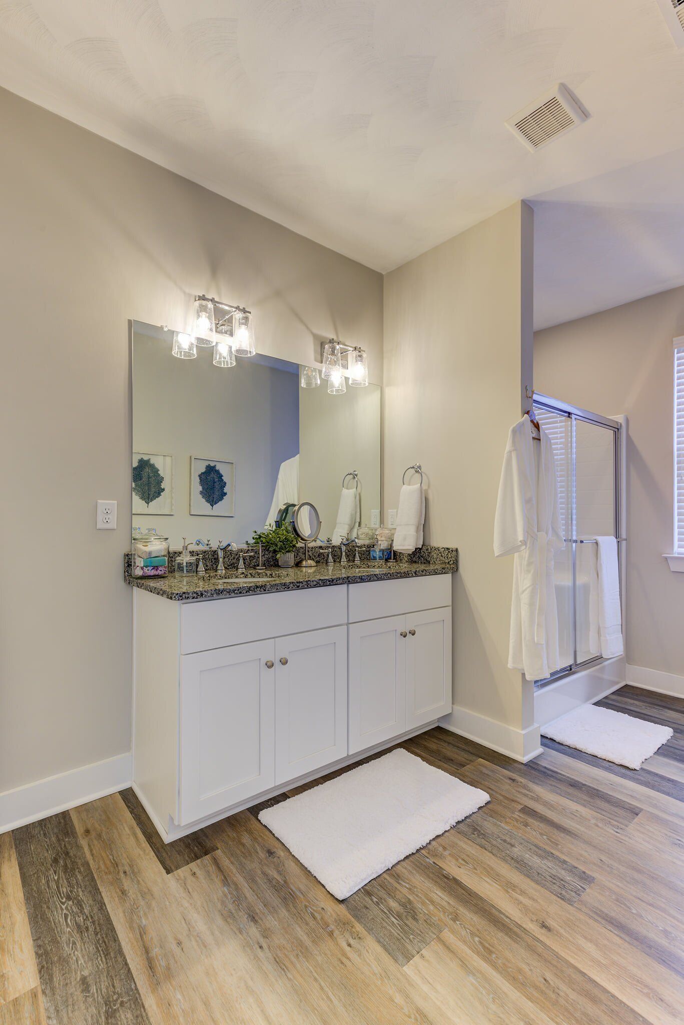 A bathroom with a double vanity, a large mirror, and a shower area.