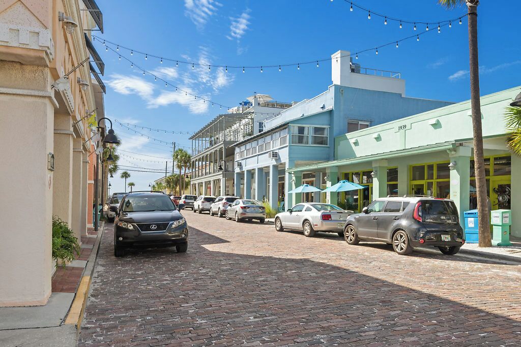 Una calle adoquinada flanqueada por vehículos estacionados y edificios.