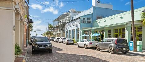 Una calle adoquinada flanqueada por vehículos estacionados y edificios.