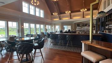 A spacious bar area with high ceilings and large windows offering a view of the outdoors.