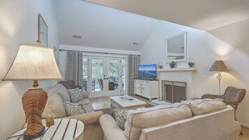 A living room with a sofa, a coffee table, a lamp, a television, and a fireplace.