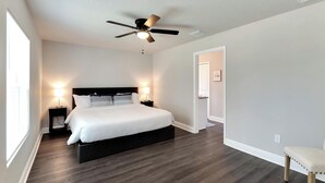 A bedroom with a bed, bedside lamps, a ceiling fan, and a bench. - 6506 N 22nd St (Tampa)