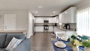 A modern kitchen with white cabinets, a stainless steel refrigerator, and a microwave. - 6506 N 22nd St (Tampa)
