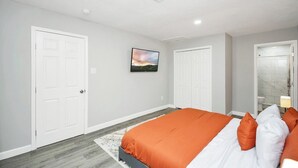 A bedroom with a bed, two doors, a picture on the wall, and a bathroom visible through an open door. - 5BR 3BA Home With Hot Tub Near Stadiums & Airport (Houston)