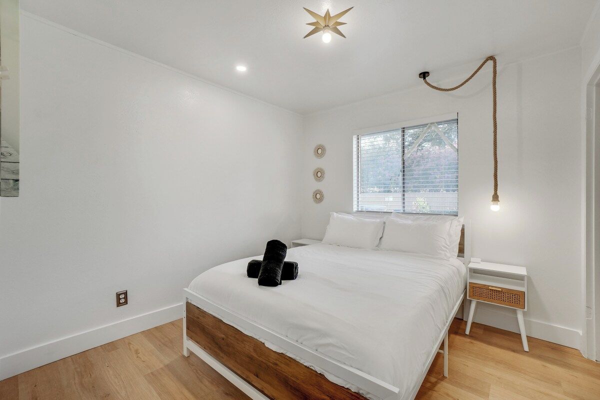 A bedroom with a bed, a nightstand, a window, and a star-shaped ceiling light.