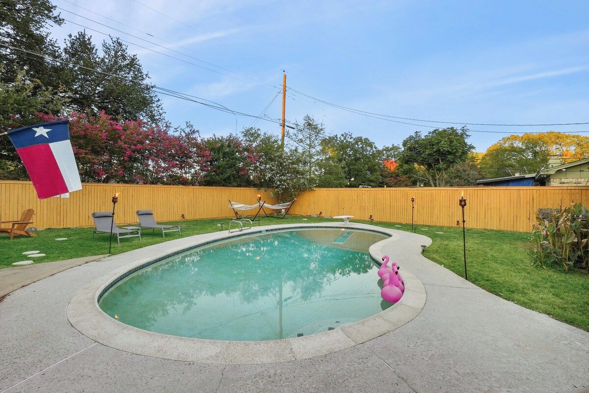 A backyard with a swimming pool, a flag, and a flamingo float.