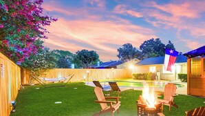 Un giardino con piscina, lettini, un braciere e una bandiera.