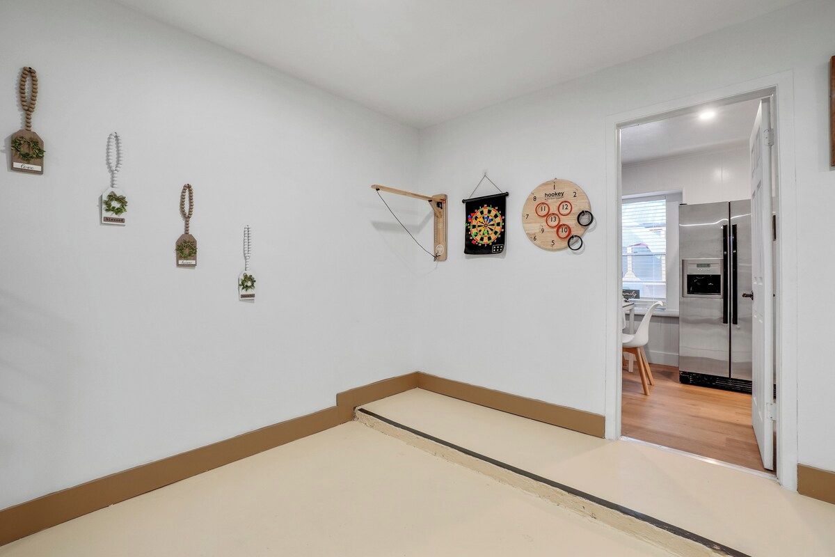 A room with a white wall, a door leading to another room, and a small table with a chair.